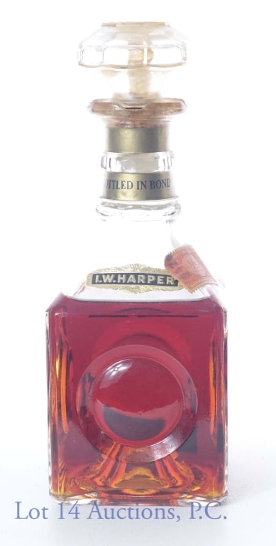 1957 I. W. Harper Bonded Bourbon Whiskey: 1957 (Bottled) Bottled in Bond I. W. Harper Kentucky Straight Bourbon Whiskey. 100 proof, 4/5 quart. Tax strip is intact between stopper and bottle, but torn below bottle neck. Please see photos for c