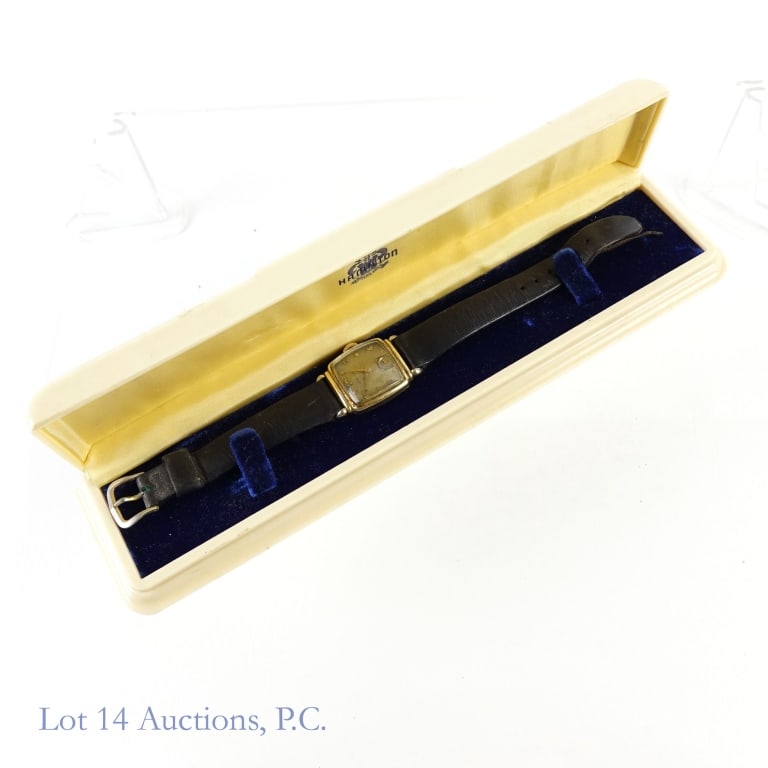 Hamilton Tank Watch, Bakelite Box: Hamilton Tank Watch, Bakelite Box. 14K gold filled on case back. Kreisler leather band. Movements function. Hamilton on face. "H" on crown. 1" x 1". Wear and tear apparent on watch, band and box. See
