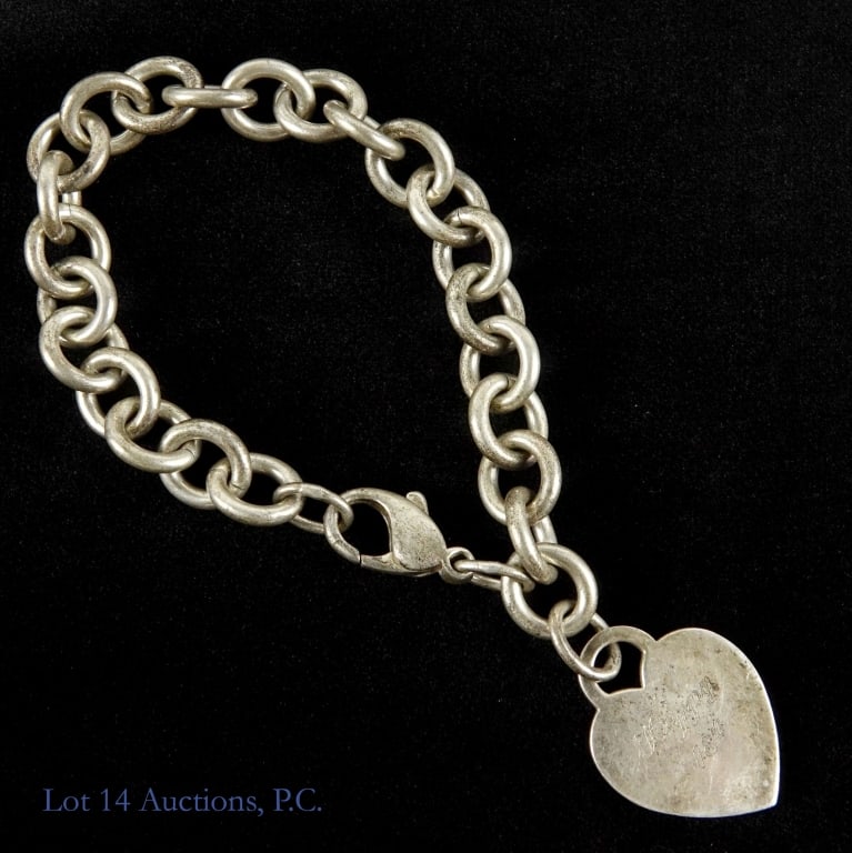 Tiffany & Co Sterling Silver 18th Bday Bracelet: Chain link bracelet with a heart charm. Back of heart charm is stamped "Tiffany & Co. 925". Charm is engraved "Happy 18th". Approximately 7.25" long. Weight: 34.5 grams. Some tarnish and wear.