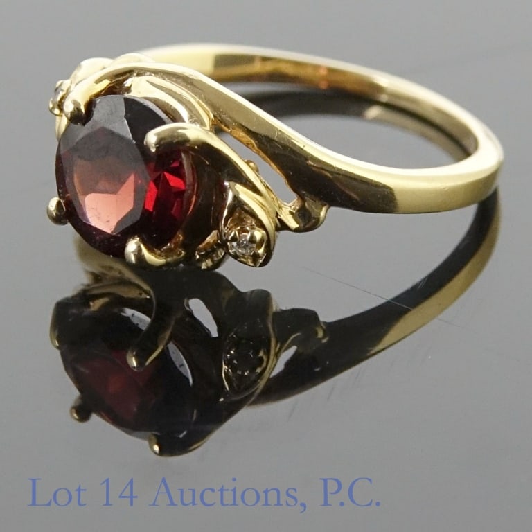 14k Yellow Gold Garnet Ring: Yellow gold ring with large central red stone and two small colorless stones. Marked "14k" and tests electronically as 14 karat gold. We were unable to assess the two small colorless stones, but the c