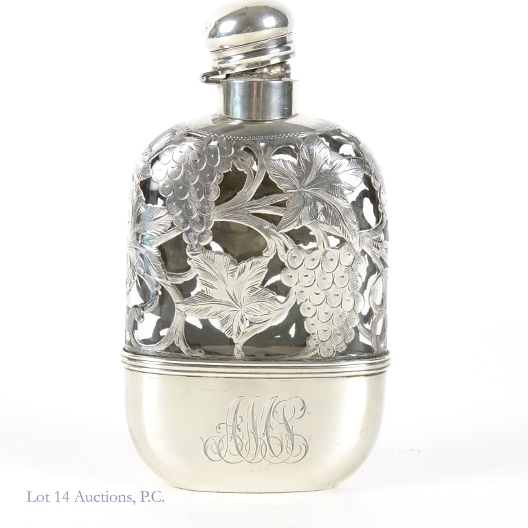 Sterling Monogram Liquor Flask: A sterling monogram liquor flask with engraved grapevine design motifs and a hinged, screw-tight lid. The bottom is marked "Sterling" and "4173". Creator's logo and pint number also on the marked, but