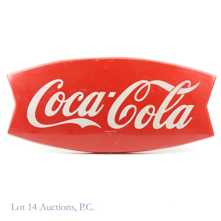 1960s Fishtail Coca-Cola Sign: Vintage SST sign in the "fishtail" style, advertising Coca-Cola. Beneath the logo, it reads: "Trade-Mark / AM 75". The sign is 26''x12''x1''. Some scratches, dents, and signs of wear & tear, but color