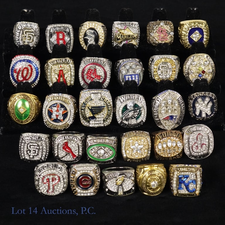 Replica Championship Rings MLB, NFL, NHL (29): 29 various replica MLB, NFL and NHL championship rings. Various sizes between 10 and 15. Each ring weighs between 1oz and 4oz. Total weight 5.5lbs. See photos for details. Box not included.