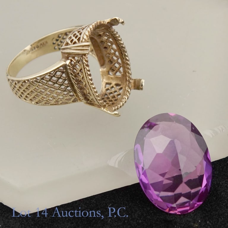 10K Y Gold Kimberly Purple Sapphire Ring (21.6 ct): Yellow gold ring marked "10k" and "Kimberly". Large purple stone tests electronically as sapphire. Stone has separated from the ring. Size: 7.5. Ring metal weight: 4.73 grams. Stone weights 21.6 carat
