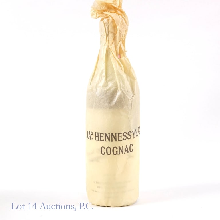 60s/70s Hennessy Cognac: Jas. Hennessy & Co. Tri Star Cognac. 4/5 Quart, 84 Proof. Series 112 1961-1977 tax strip fully intact. Low shoulder fill. Original wrapping paper with the order form for Hennessy branded snifter glass