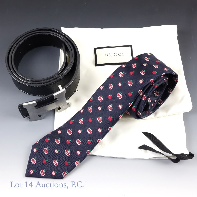 Hermes Leather Belt, Gucci Tie Men's Accessories: Two vintage designer accessories for men. The first is a leather belt with an H-shaped belt buckle from Hermes. The second is a silk tie with an apple design from Gucci. Both held in a white cloth bag