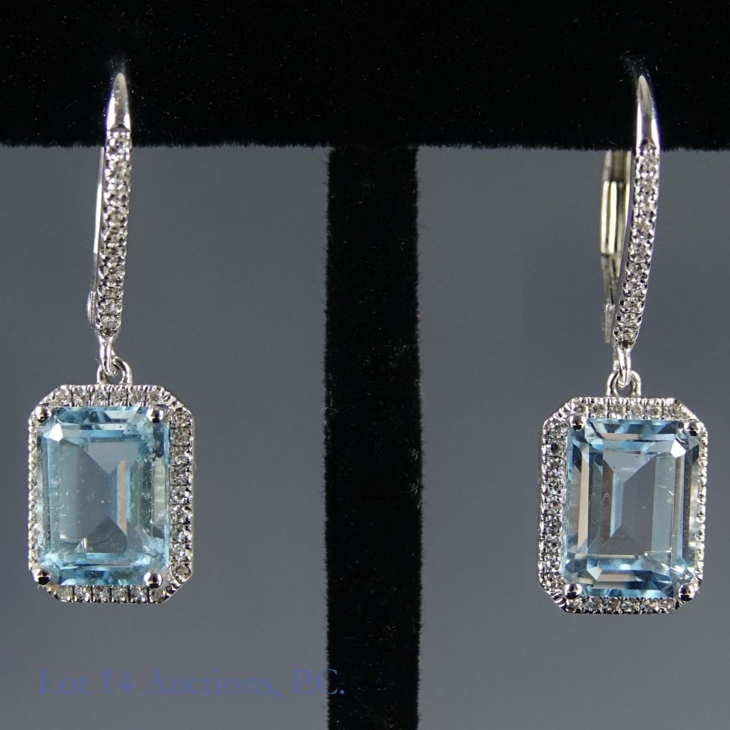 14k White Gold Topaz & Diamond Earrings: Pair of earrings made of 14k white gold decorated with rectangular cut blue topaz stones surrounded by tiny melee diamonds. Both earrings together weigh approximately 3.37g or 0.11 troy oz.