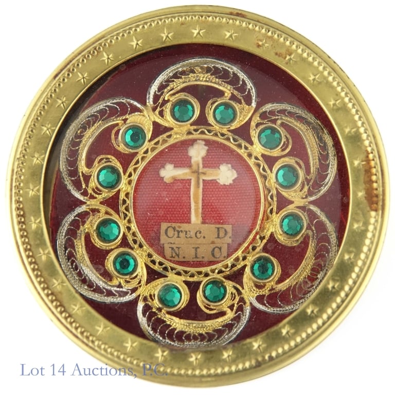 Catholic Silver Reliquary - Cruc. D. N.I.C.: Reliquary containing relic marked "Cruc. D. N.I.C.". Includes brass and glass 2" diameter case containing 1.5" silver (gold tone) reliquary with filigree and green gems / glass stones. Back of reliqua