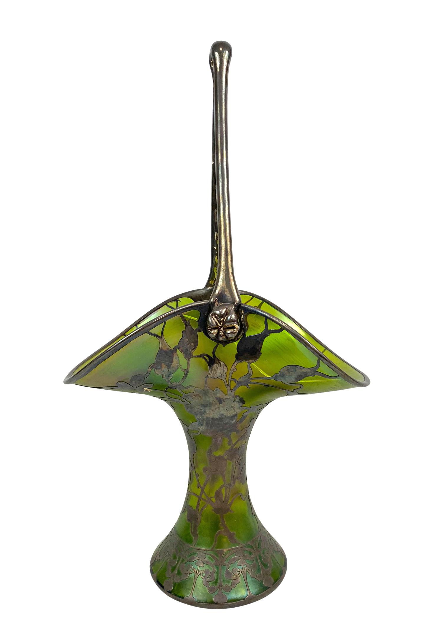 Moser Art Nouveau Silver Overlay Basket Vase: Antique Moser green glass handled basket vase designed with a beautiful Art Nouveau floral silver overlay throughout. Circa: Turn of The Century. Measures approx. 19-3/4" H x 11-3/8" W x 7-1/8" D. Tot