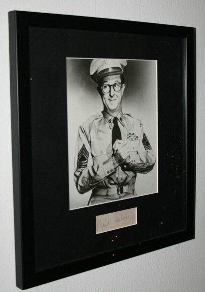 Phil Silvers - Autograph: A fantastic b/w photographic print of Phil Silver's dressed as his scheming character Sgt Bilko with Phil Silver's autograph tastefully mounted. Framed and Glazed