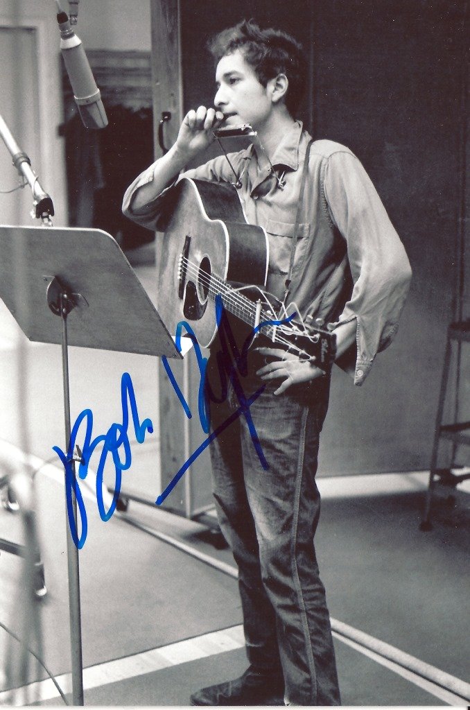 Promotional photograph of Bob Dylan’s first Columbia: Bob Dylan. A promotional photograph of Bob Dylan’s first Columbia recording session of 1962. Signed in blue sharpie by Bob Dylan D. 4 x 6”