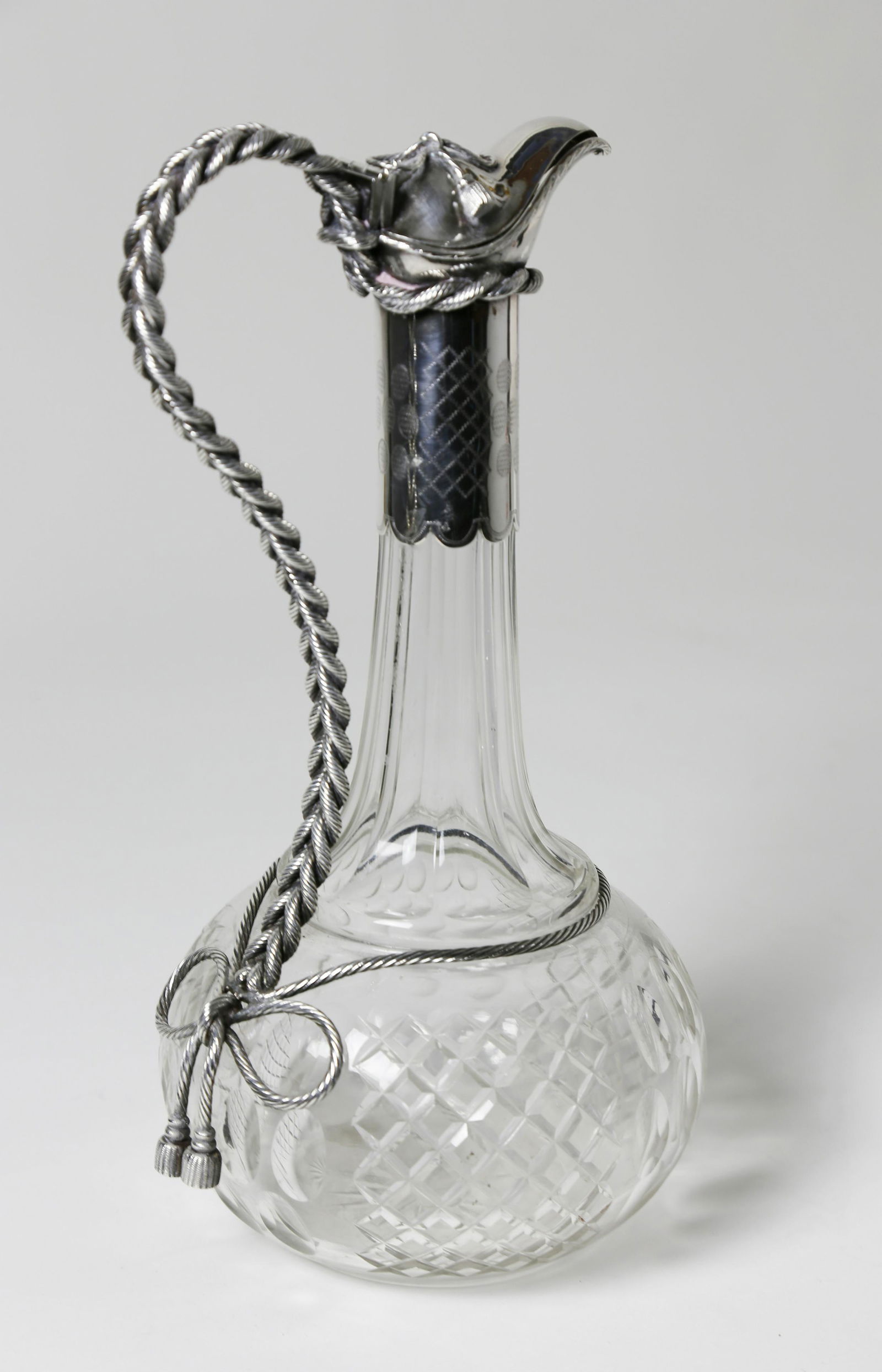 Silver Plate and Cut Crystal Cruet, 19th Century: Silver Plate and Cut Crystal Cruet, 19th Century, long neck with graceful rope twisted handle from a bow tied hinged cover to a bow tied and tasseled cable, on a cut bottle of paneled thumbprint and h