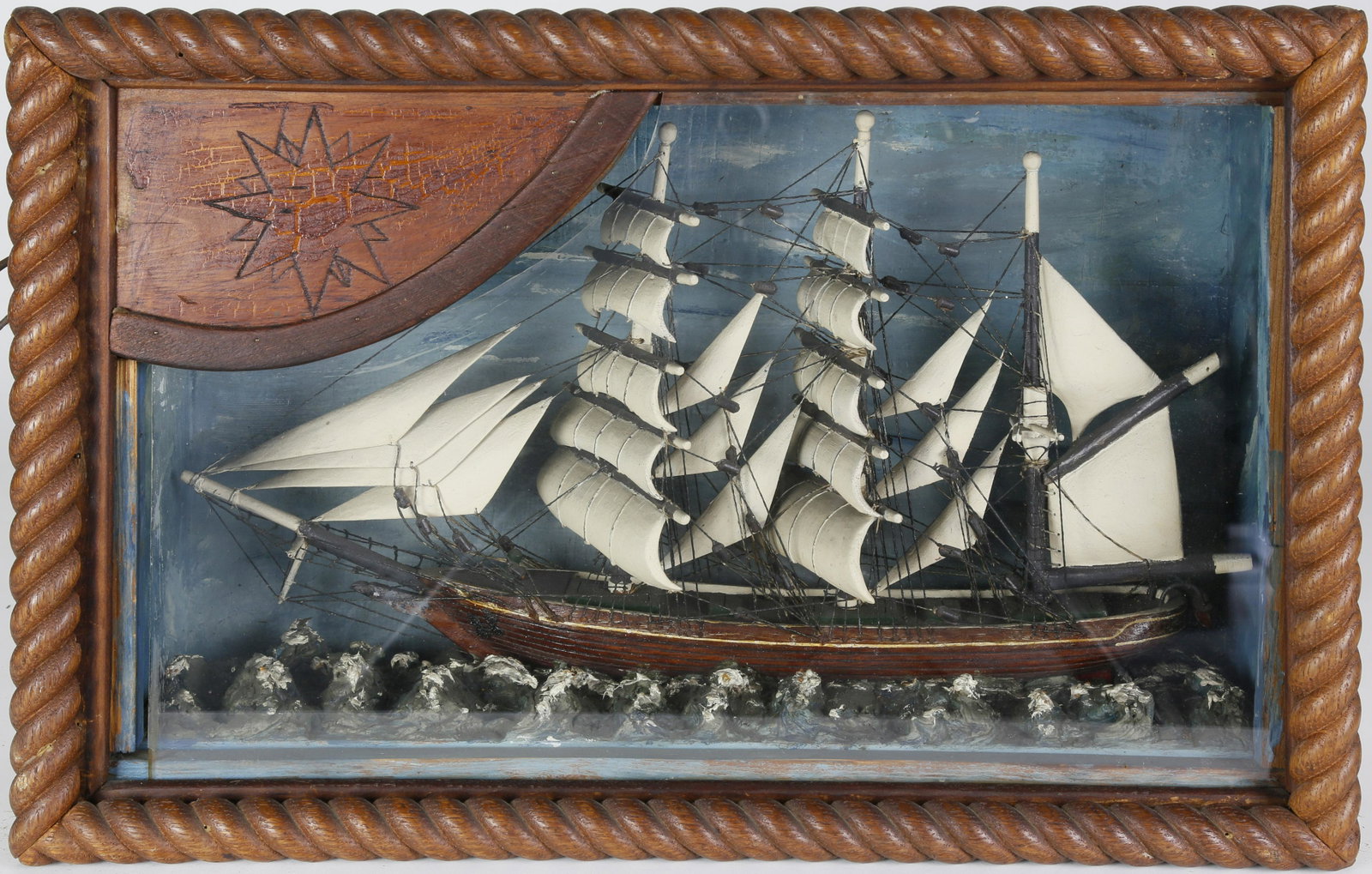 Folk Art Ship Shadowbox, circa 1950s: Folk Art Ship Shadowbox, circa 1950s, three-masted fully rigged vessel on high ocean caps, in a carved rope frame, electrified. Height 12 ½ in. Width 19 in. Depth 6 in.