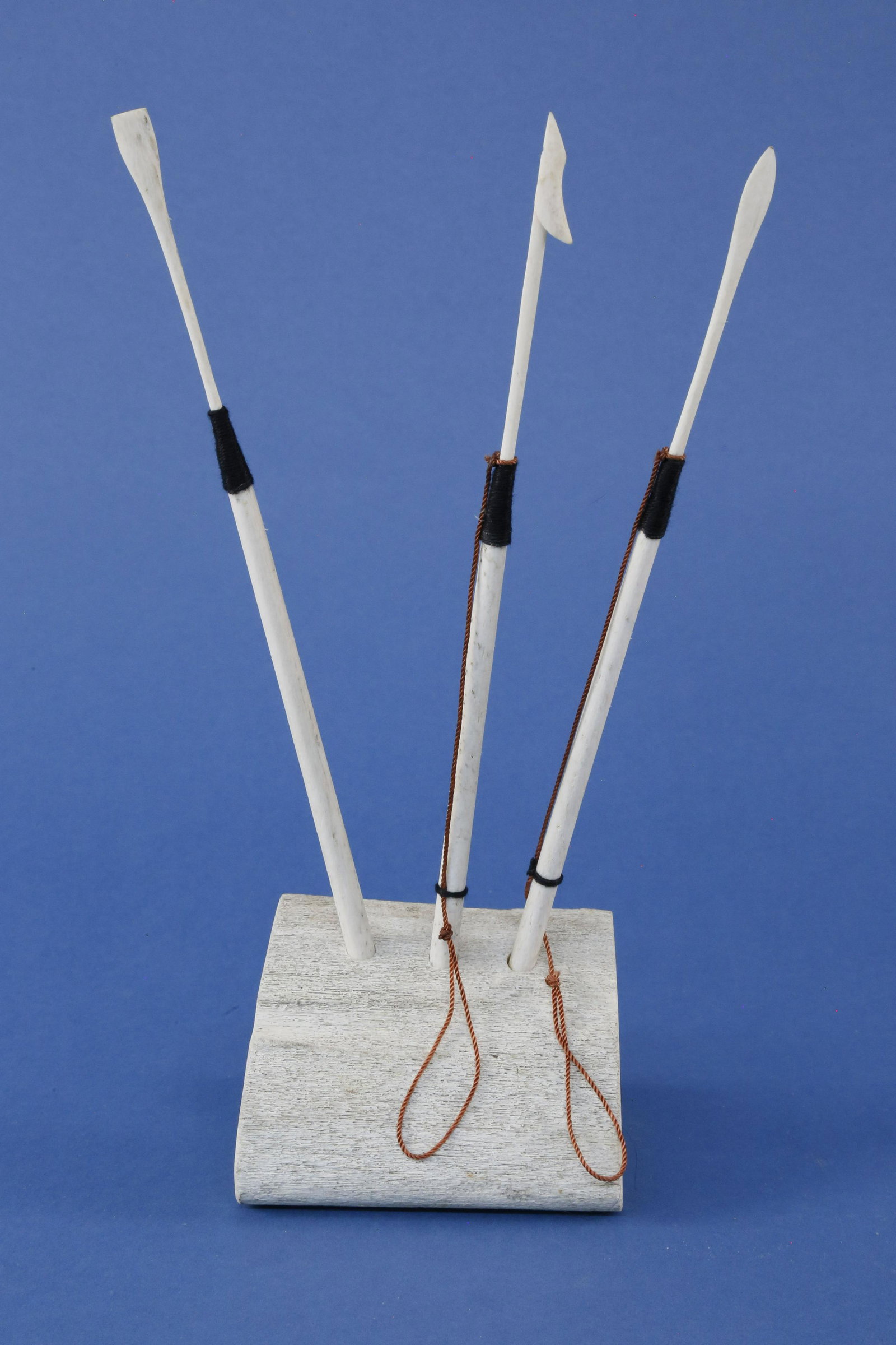 Three Contemporary Miniature Bone Whaling Tools: Three Contemporary Miniature Bone Whaling Tools, including a killing lance, toggle harpoon, and a blubber spade, knotted on a whalebone stand Height 10 in.
