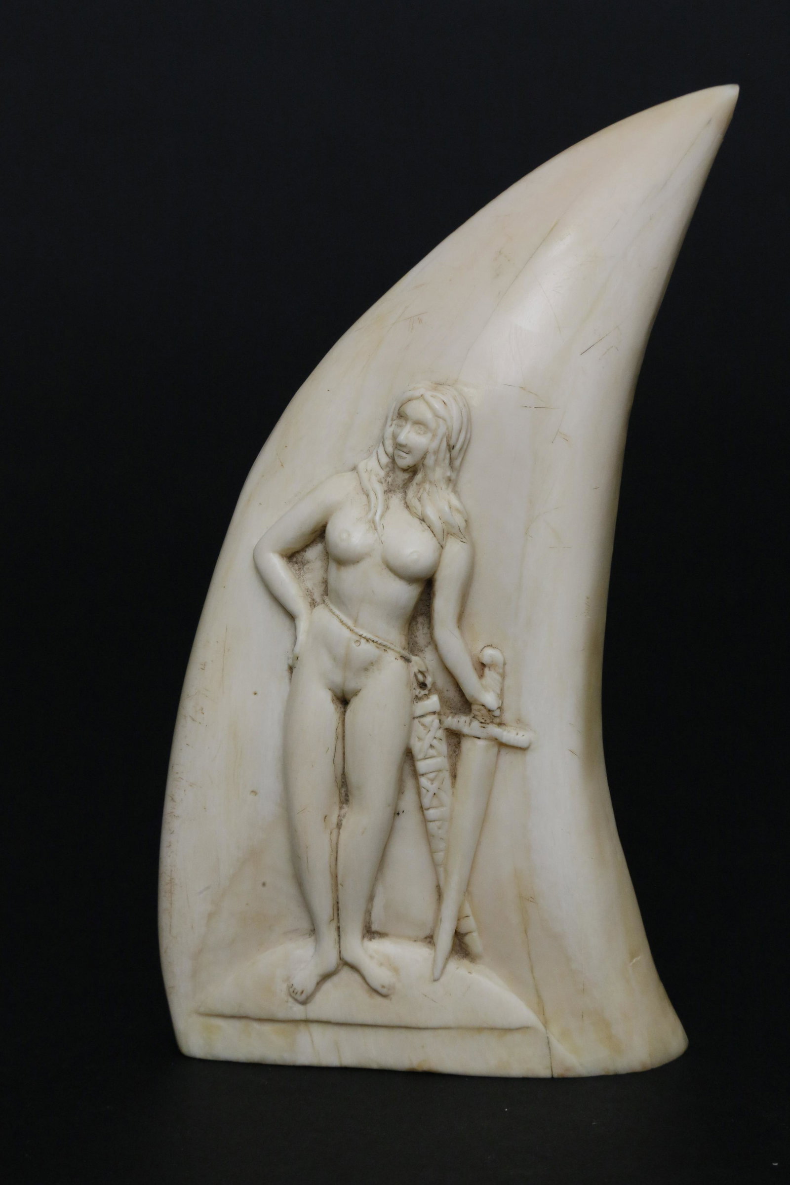 Nude Female Bas-Relief Carved Antique Whale Tooth: Bas-Relief Carved Antique Whale Tooth, circa 1840, full portrait of a standing nude woman with flowing hair and holding a sword Height 6 in.