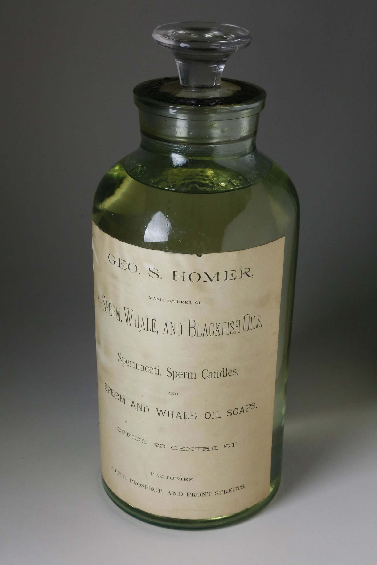 George S. Homer Rare Large Bottle of Blackfish Oil: George S. Homer (1838-1912) Rare Large Bottle of Sperm, Whale and Blackfish Oils, New Bedford, circa 1850-1860, the stoppered clear colorless glass two-part mold-blown bottle with seal intact. Printed