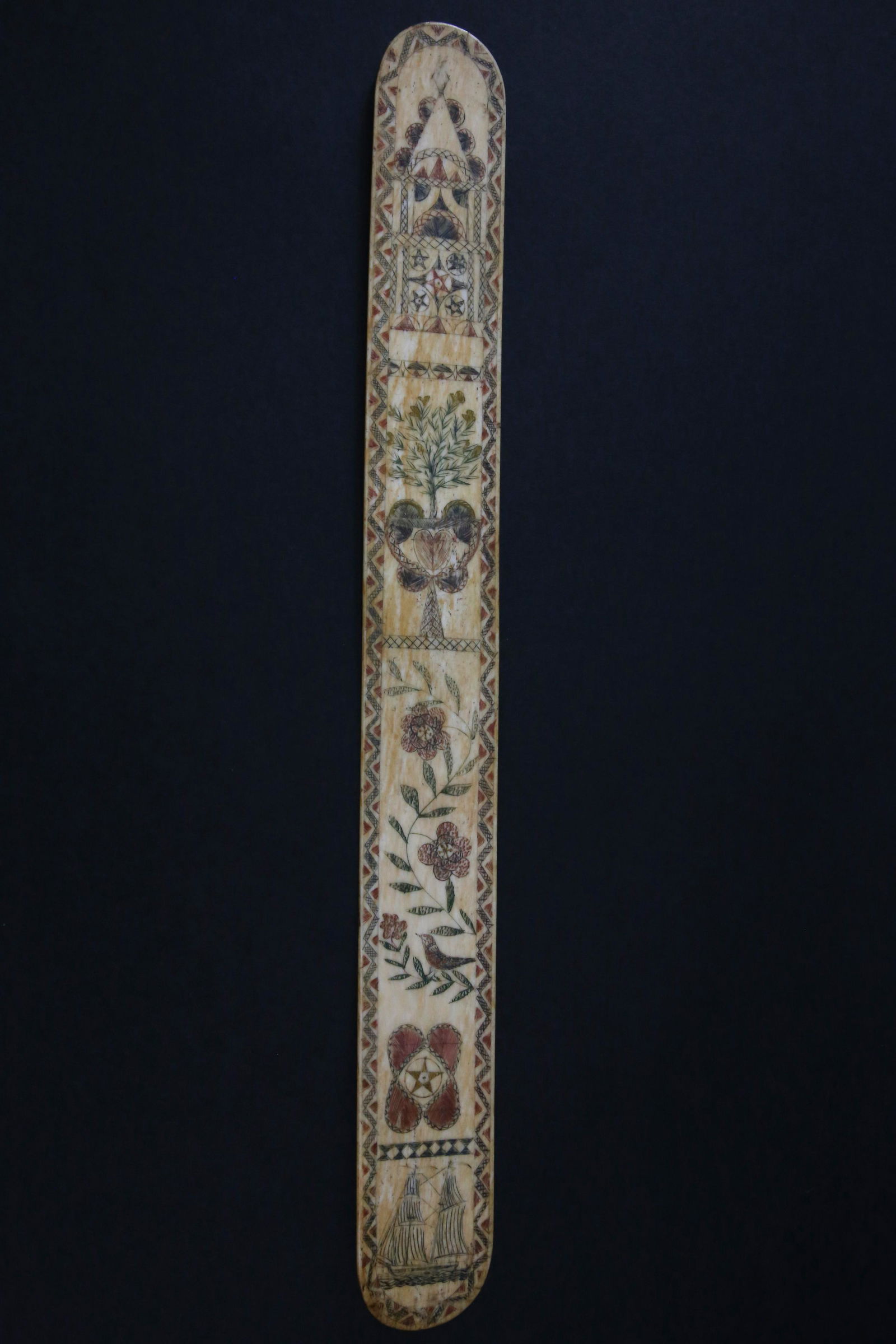 Whaleman Scrimshawed Polychrome Antique Whalebone Busk, circa 1860: Whaleman Scrimshawed Polychrome Antique Whalebone Busk, circa 1860, engraved with a bark, bird on foliage, heart, planter with tree, 5-point stars, etc.; encompassed within a zigzag and diamond border