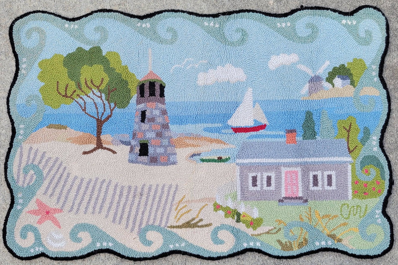 Vintage Claire Murray New England Coastal Scene Hooked Rug: Vintage Claire Murray New England Coastal Scene Hooked Rug, with lighthouse, windmill, Cape style house and sailboat, with original label on reverse. 24 in. x 36 in.