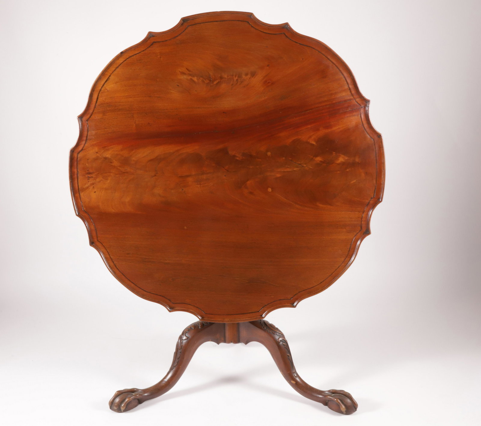 George III Oversized Mahogany Tripod Table, 18th Century: George III Oversized Mahogany Tripod Table, 3rd Quarter of the 18th Century, scalloped shaped circular top tilts over fluted and acanthus scroll-carved cabriole tripod ending in claw and ball feet; ex