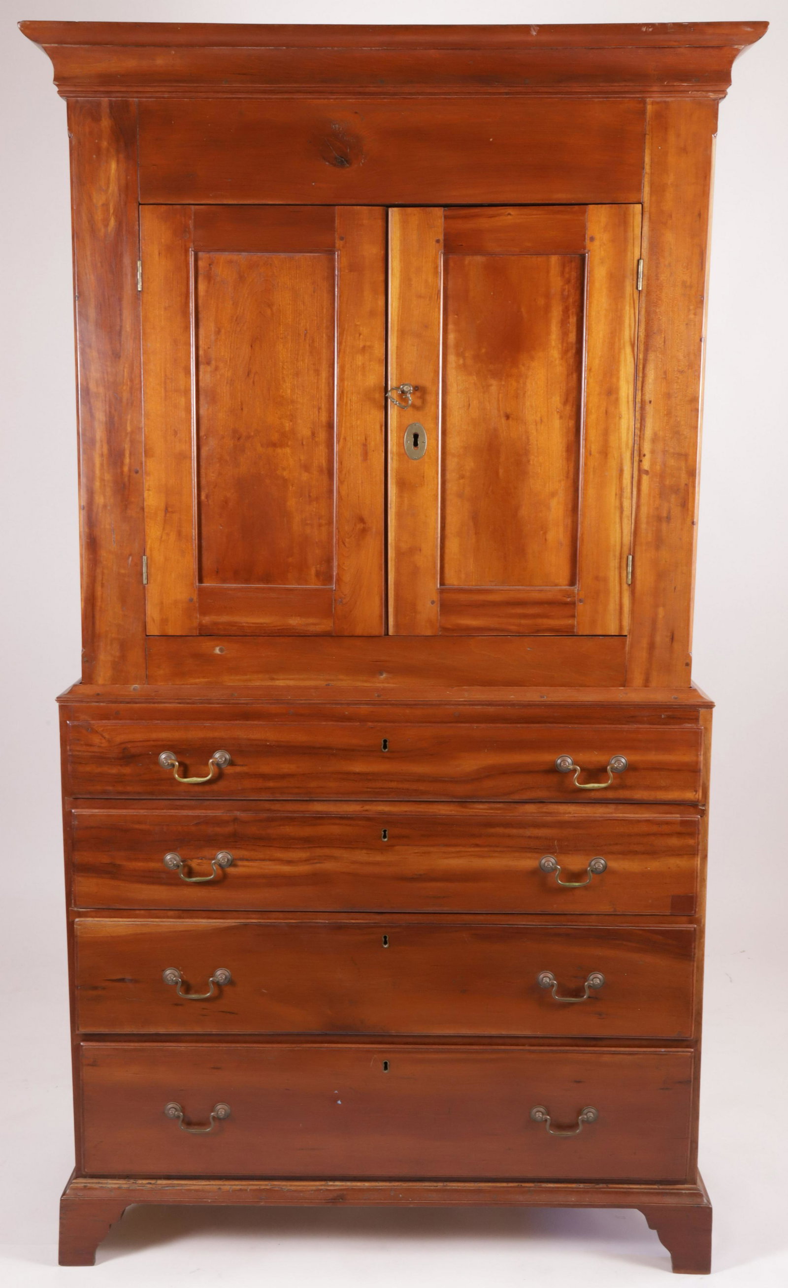 New England Federal Cherry Linen Press, early 19th Century: New England Federal Cherry Linen Press, early 19th Century, the upper section with cupboard doors and shelves over four graduated drawers with post and bail handles on ogee bracket feet Height 73 in.