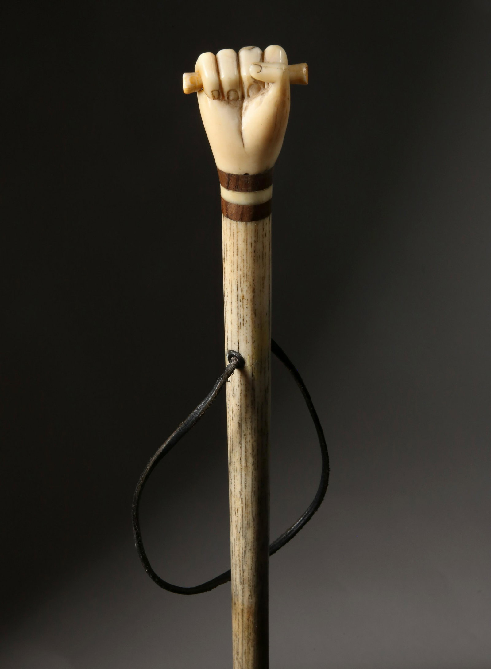 Whaleman Made Clenched Fist Walking Stick, circa 1850: Whaleman Made Clenched Fist Walking Stick, circa 1850, the carved antique whale ivory clenched fist grasping a scroll above two tropical wood spacers on a whalebone tapering shaft with eyelet, ending