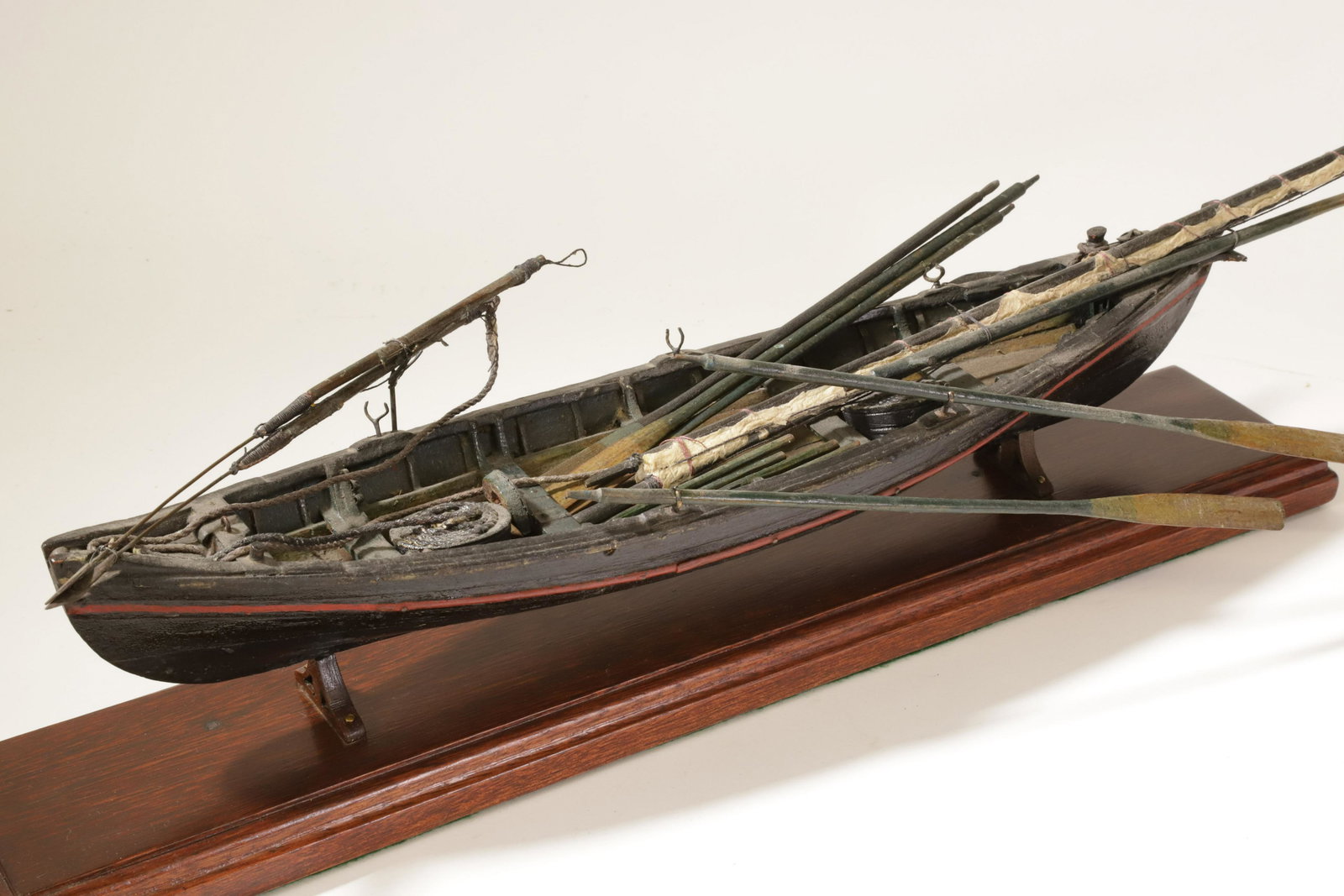 Wooden Model of a Whaleboat 20th Century: Wooden Model of a Whaleboat, 20th Century, black painted hull with red rail, complete with harpoons, lances and other implements, two tubs of line, oars, mast with sail, ect. displayed on a cradle and