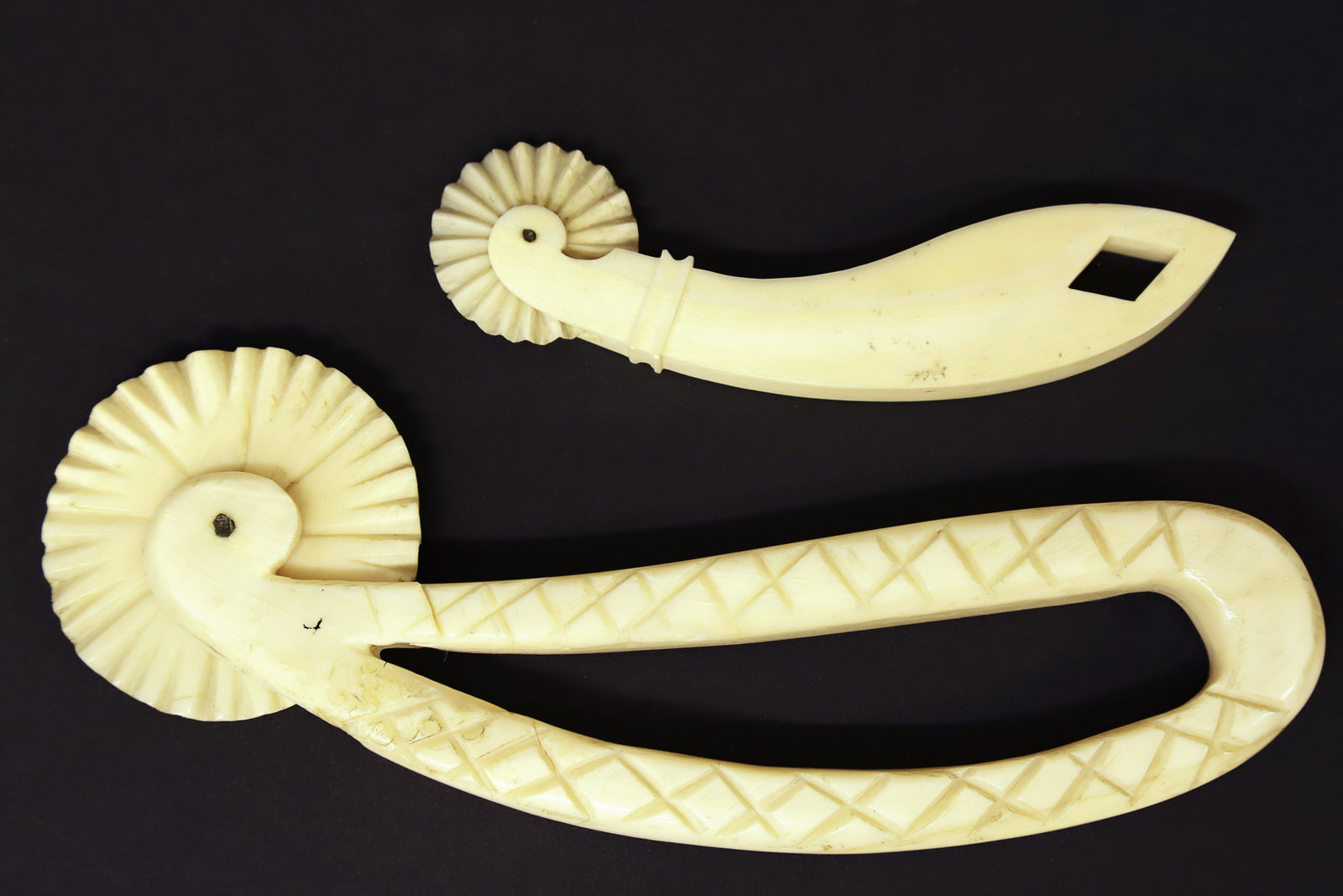 Two Antique Whaleman Made Pie Crimpers, 19th Century: Two Antique Whaleman Made Pie Crimpers, 19th Century, each with curved handles and solid zigzag wheels; the larger crimper with open handle and cross-hatch carvings, the smaller with diamond shaped cu