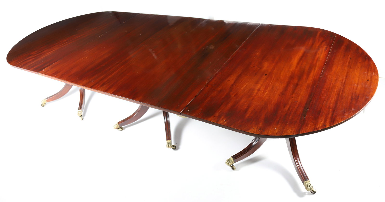 Antique English Regency Mahogany Triple Pedestal Dining Table, 19th Century: Antique English Regency Mahogany Triple Pedestal Dining Table, 19th Century, with two hand carved leaves, turned standard continuing to reeded down-swept pedestal legs ending in brass paw casters Heig