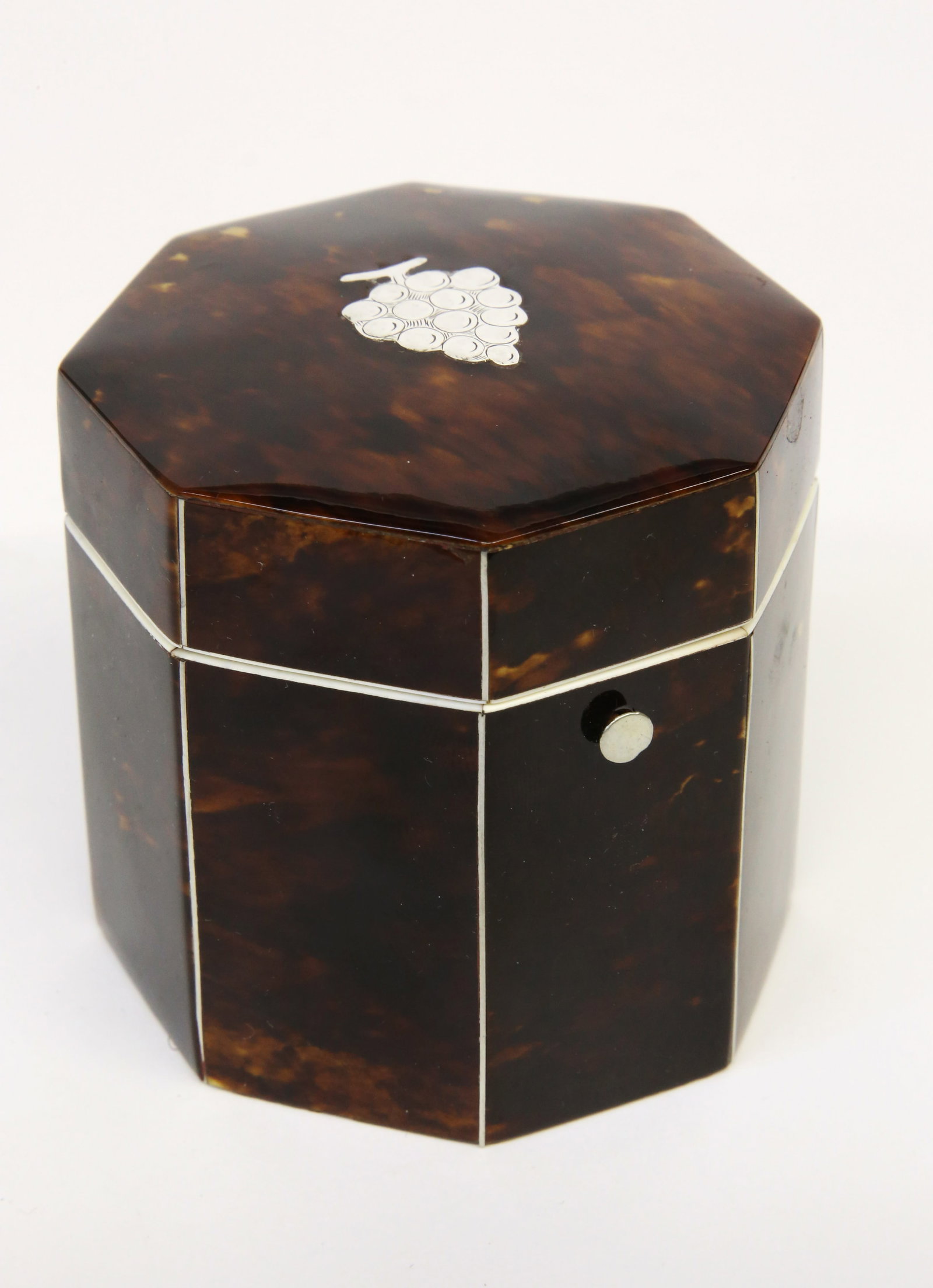 British Regency Antique Tortoiseshell Octagonal Tea Caddy, 19th Century: British Regency Antique Tortoiseshell Octagonal Tea Caddy, 19th Century , with silver line inlay and silver cluster of grapes on lid; lacking interior cover Height 3 in. Width 3.25 in. Provenance: The