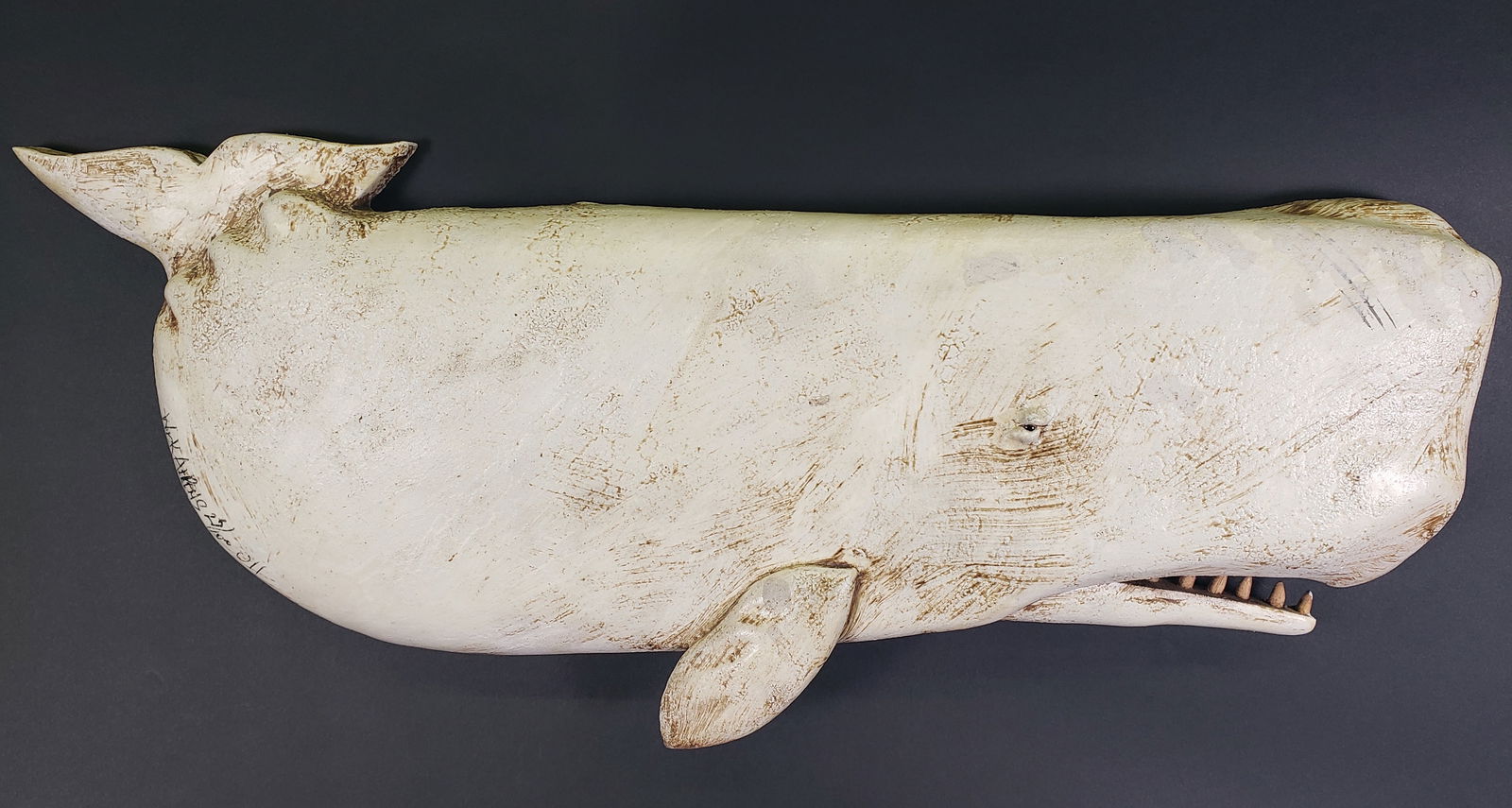 Wick Ahrens Carved and Painted Moby Dick Sperm Whale Plaque: Wick Ahrens (American 1944-2016) Carved and Painted Moby Dick Sperm Whale Plaque, tail up, inset with glass eye, individually carved teeth, signed and dated lower left, Wick Ahrens 2011 10.5 in. x 25.
