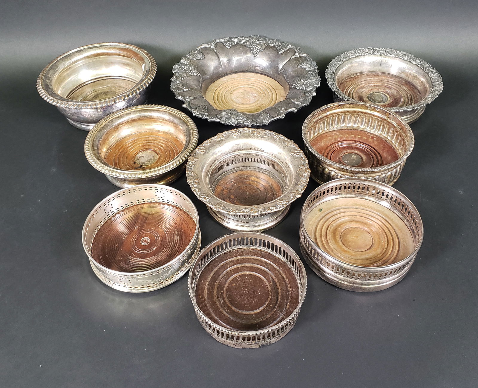 Set of Nine Antique-Vintage Silver Plated Wine Coasters: Set of Nine Antique-Vintage Silver Plated Wine Coasters, with turned oak and walnut wood bases, varying in size and styles, pierced, gadrooned and berry repousse decoration. Diameters from 8.75 in. to