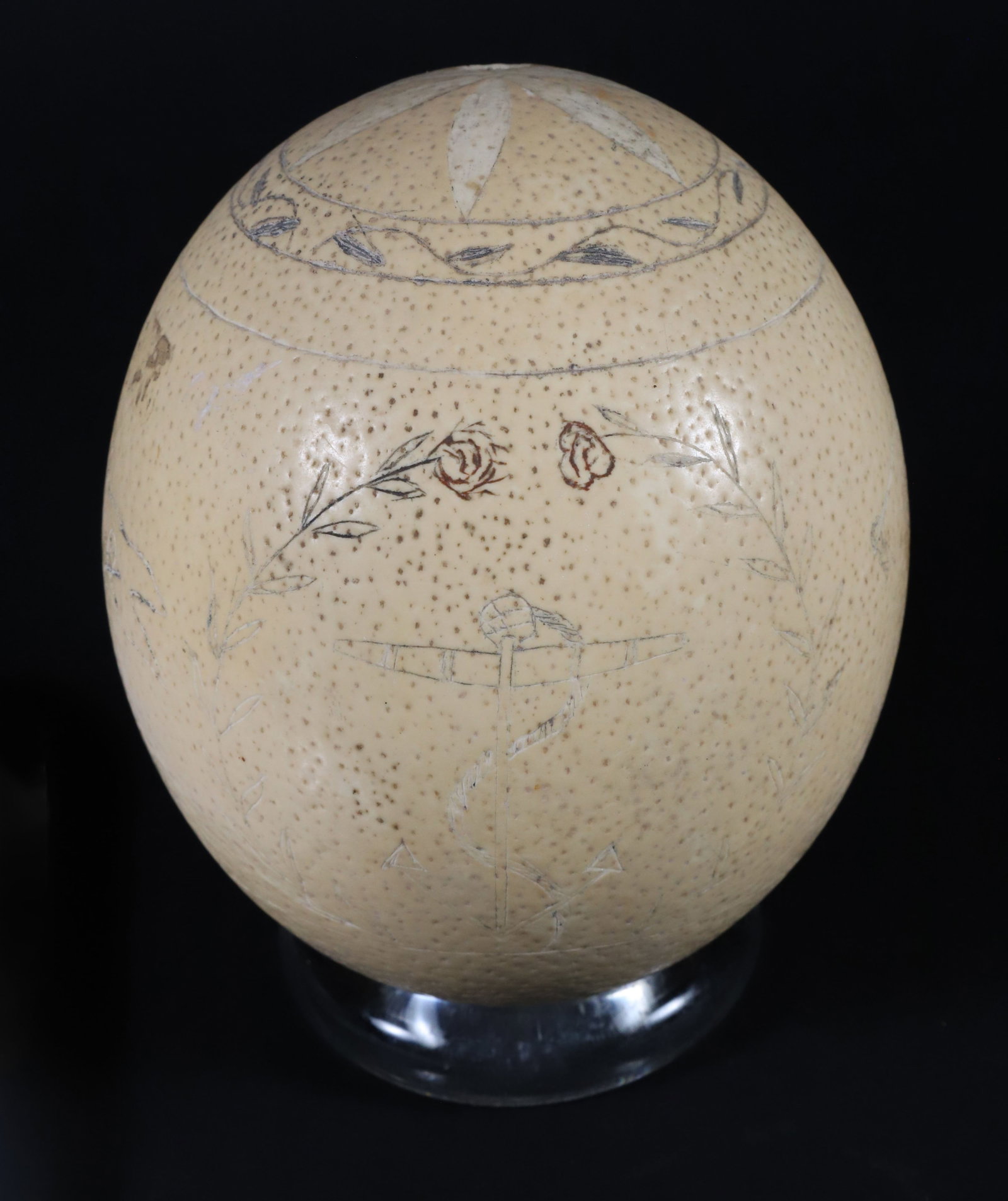 Scrimshaw Ostrich Egg Depicting Two Sailors Bearing Flags and British Sailboat: Scrimshaw Ostrich Egg, depicting two sailors bearing flags flanking a British sailboat, with stars on North and South ends Heigh 6 in. Width 5 in. Provenance: The Estate of Anne Gardner DiVenere, Nant