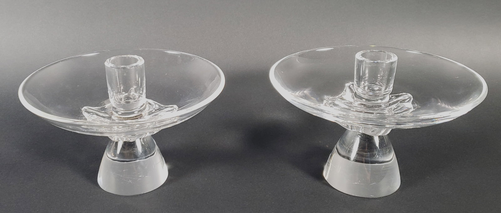 Pair of Signed Steuben Clear Crystal Candlesticks, 20th century: Pair of Signed Steuben Clear Crystal Candlesticks, 20th century, hand blown, with dish form drip basins. Height 4.5 in. Diameter 6.25 in.