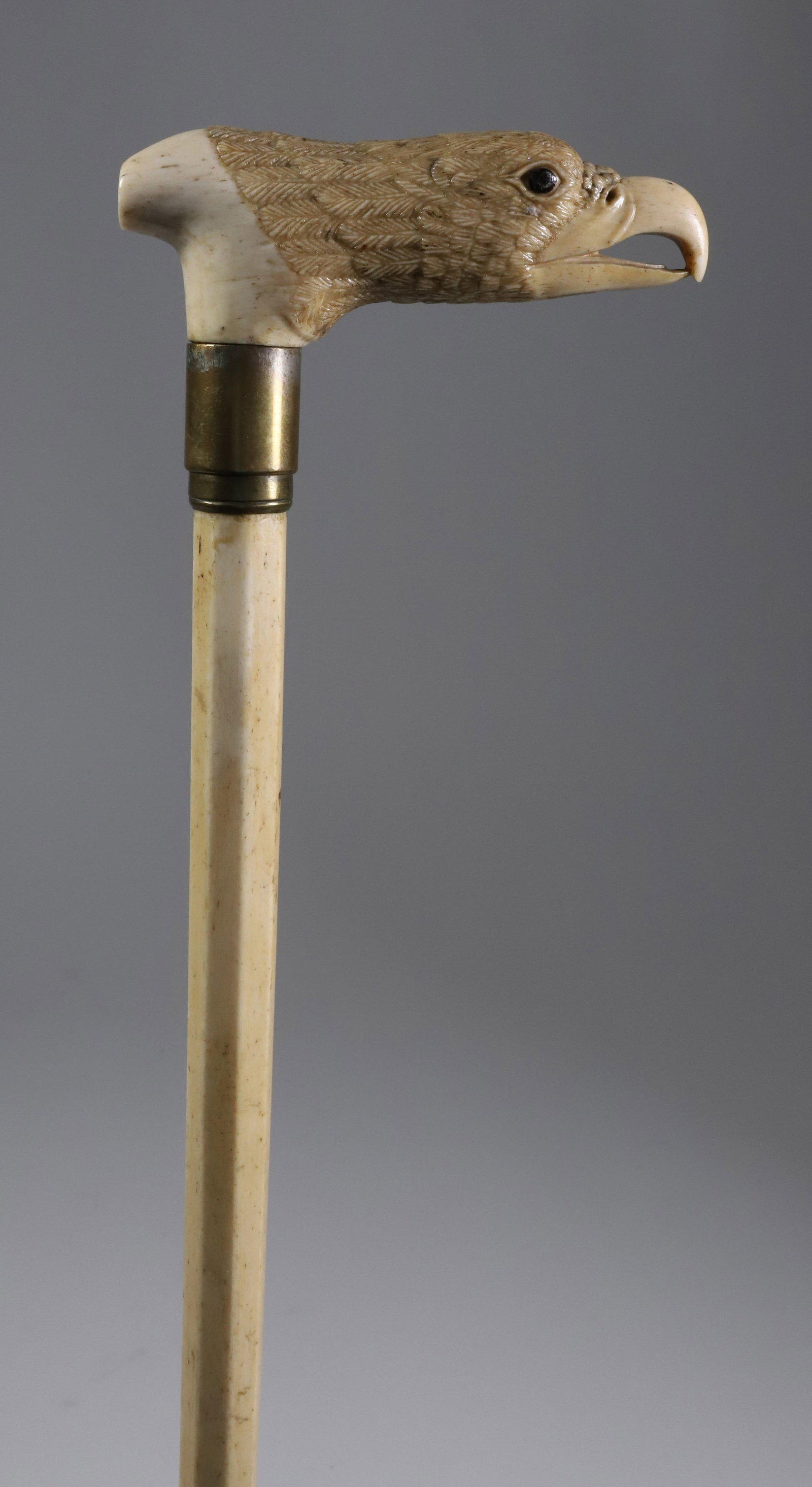 Whaler Made Eagle Grip Cane, 19th Century: Whaler Made Eagle Grip Cane, 19th Century, finely carved whale bone eagle head grip with inset eyes, brass band on an octagonal panel transitioning to a round tapering shaft Length 35 in. Provenance: