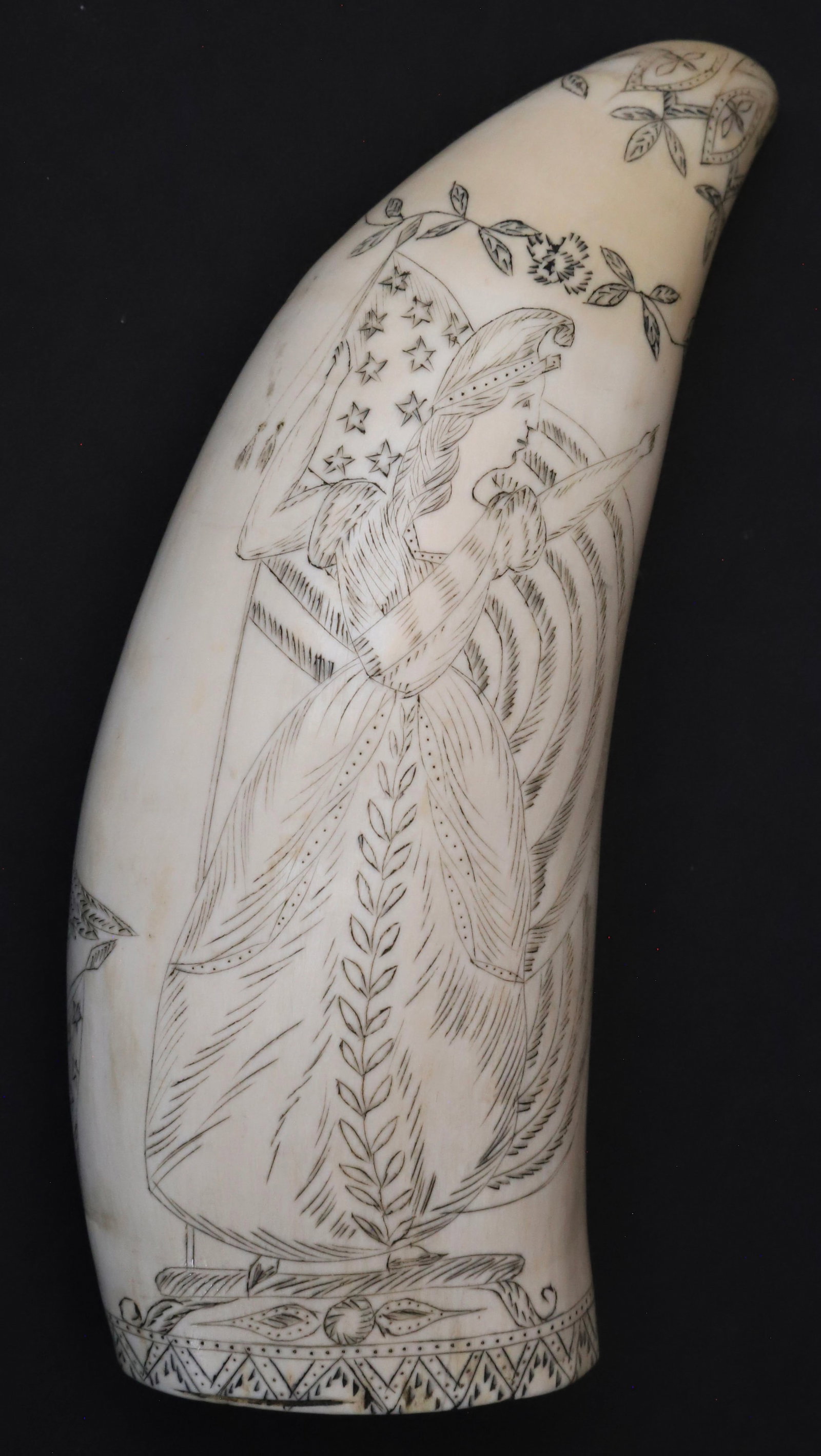 Scrimshaw Whale Tooth "Lady Liberty", 19th Century: Scrimshaw Whale Tooth "Lady Liberty", 19th Century, full portrait holding American flag, the verso with rigged bark flying colors above a spread wing eagle above a Federal Shield, flanked by six flags