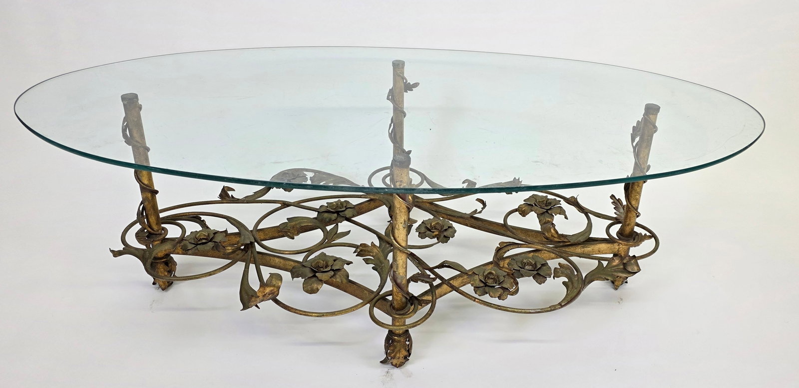 Vintage Art Deco Floral Gilt Oval Coffee Table, 20th century: Vintage Art Deco Floral Gilt Oval Coffee Table, 20th century, with surfboard shaped glass top and foliate vine work decoration to the base. Height Height 16.5 in. Width 52 in. Depth 26 in.
