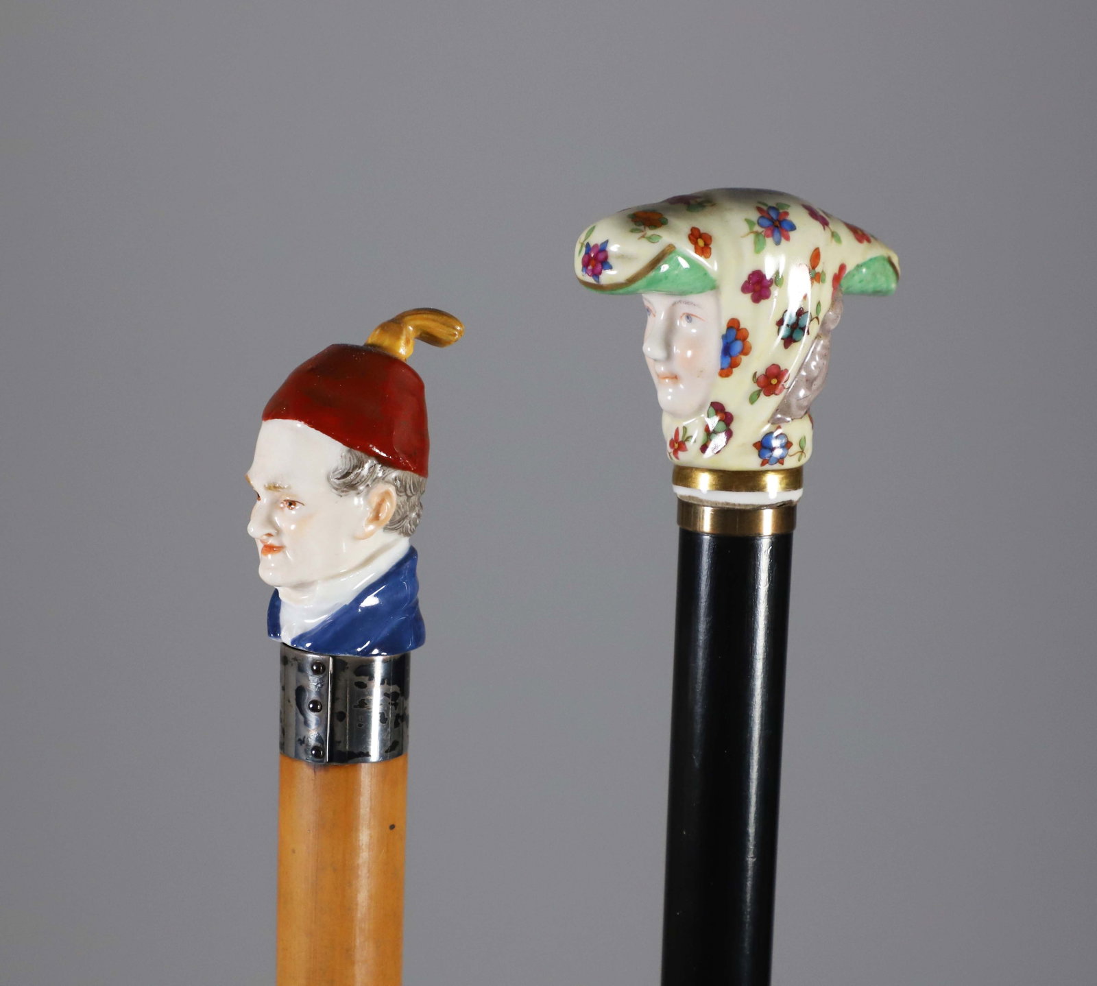 Two Continental Polychrome Porcelain Head Walking Sticks, 19th Century: Two Continental Porcelain Walking Sticks, 19th Century, bust of a gentleman wearing red cap, silver collar on malacca shaft, and bust of a woman wearing a colorful scarf on ebonized wood shaft Lengths