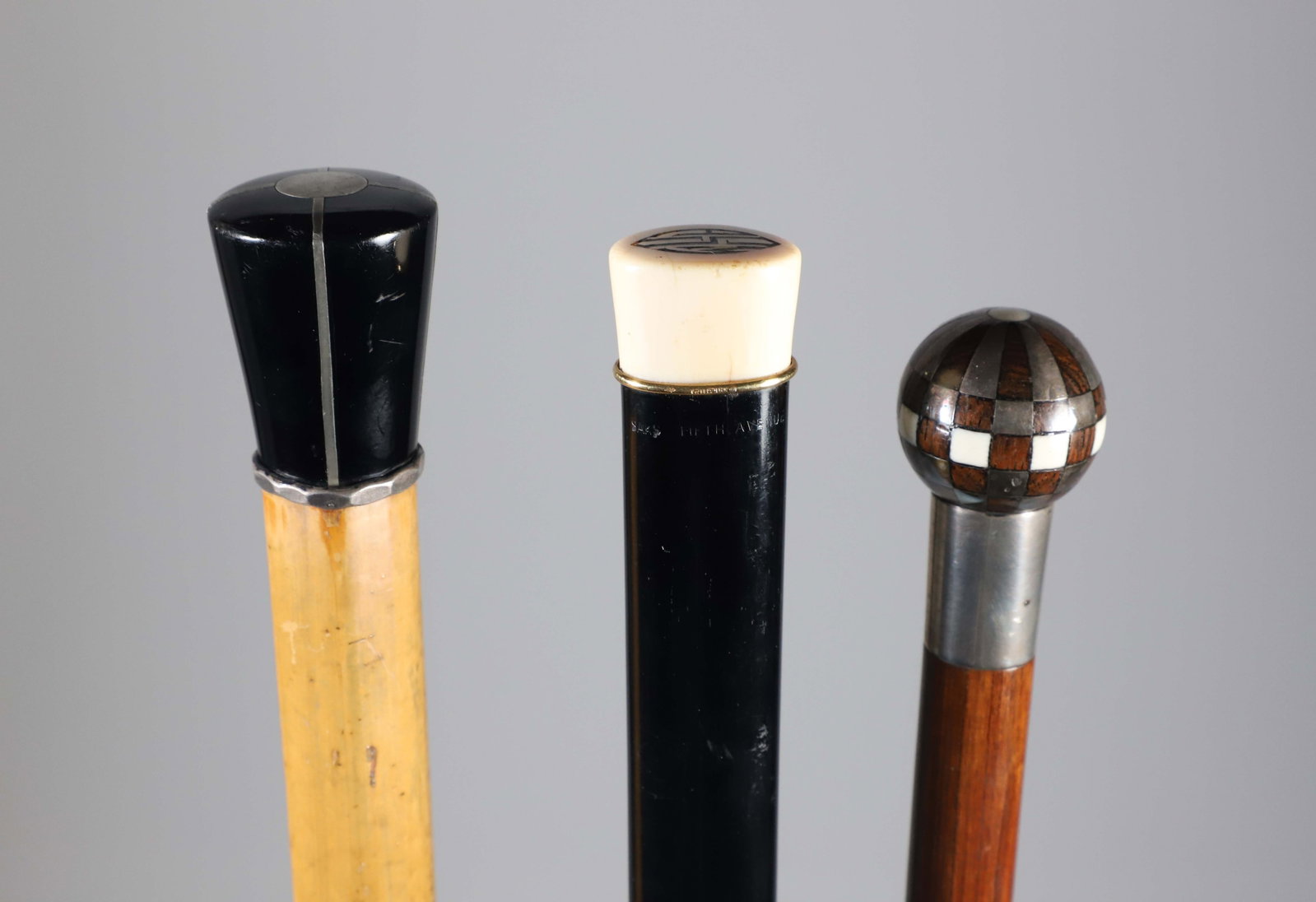 Three Vintage Walking Sticks: Three Vintage Walking Sticks, including an Art Deco black jet and silvered metal pommel grip on blonde wood shaft, an inlaid metal and wood sphere, and a monogrammed tuxedo stick. Length 36 in. Proven