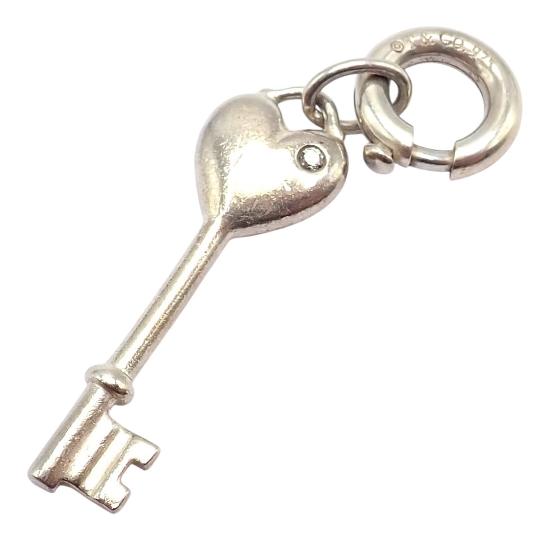 Tiffany & Co. Silver Diamond Key Heart Charm Pendant + Spring Ring Clasp: About This Piece:Tiffany & Co. silver key heart charm pendant featuring a heart-shaped top with a diamond accent and a spring ring