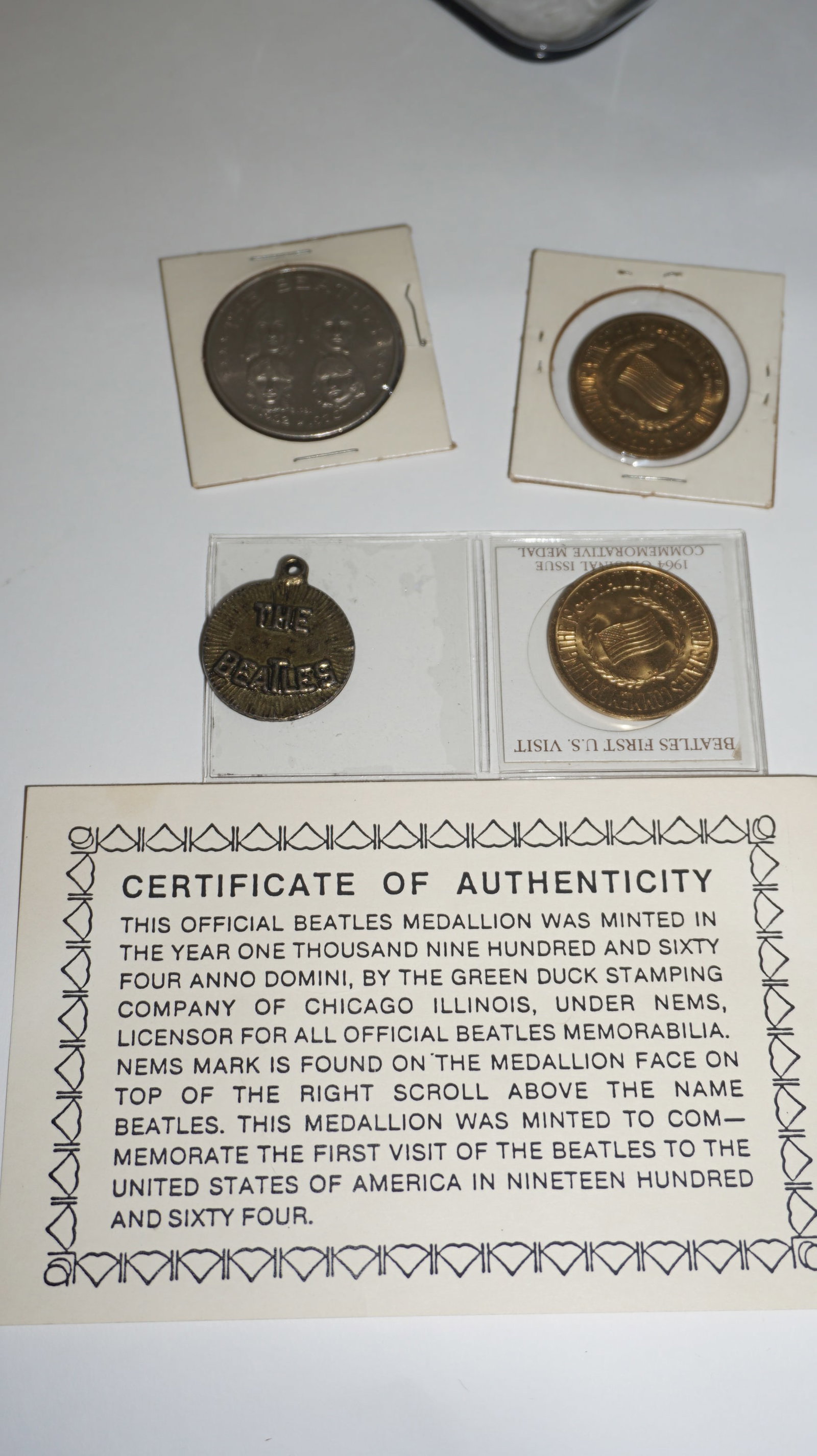 Beatles Medallion & Coin Set (4pcs): Grouping of four Beatles collectible medallions/coins including an official 1964 Green Duck Stamping Company silver-tone Beatles portrait medallion with certificate of authenticity, two bronze-tone co