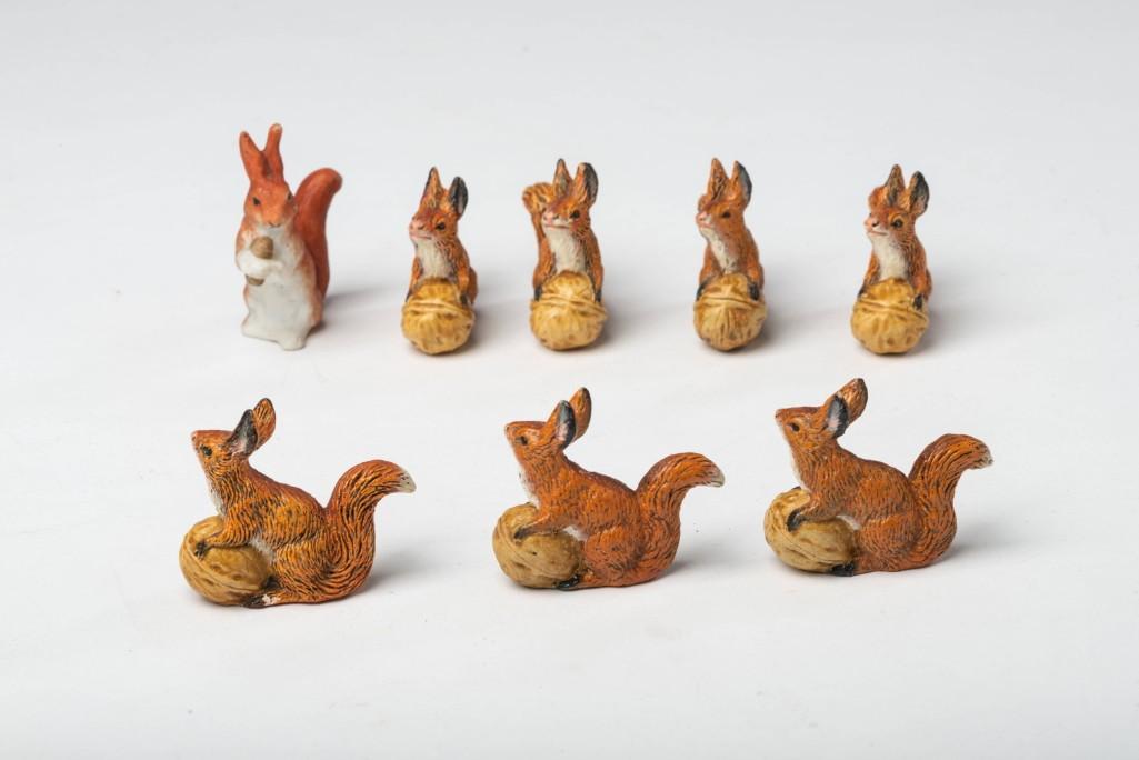 Seven Miniature German Squirrel Figurines.: Ceramic, each modeled with a walnut, height 1 5/8 inches. Together with a similar unmarked example.