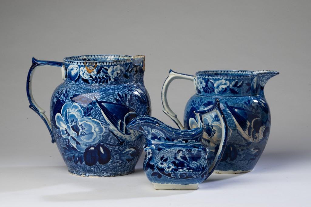 Three Early Blue and White Transferware Pieces.: With a pattern of peonies and a bird. Including two pitchers, heights 7 and 6 inches, and a creamer, height 5 inches. The pitchers is as found condition with old repairs, the creamer in very good cond