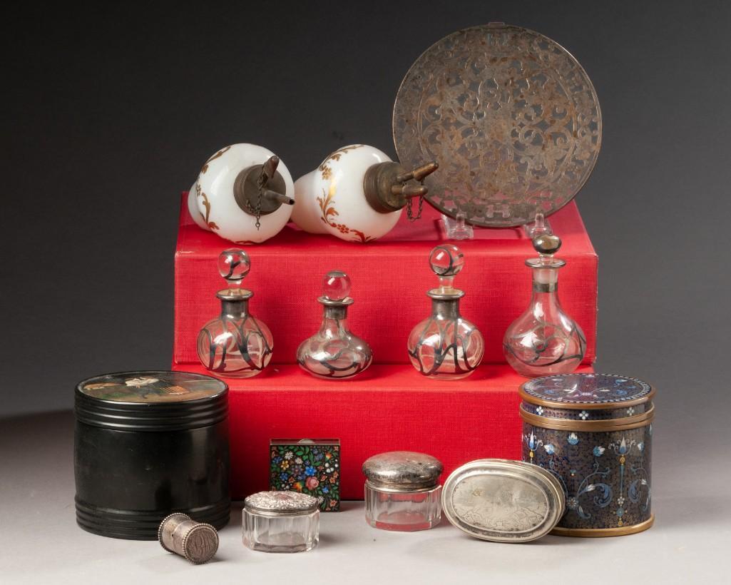 Group of Continental Table Objects.: Two peg lamps, height 7 inches, four silver overlay bottles, silver overlay trivet, snuff box dated 1860, enamel box, two glass jars with silver lids, small silver case, a Russian blue enamel canister