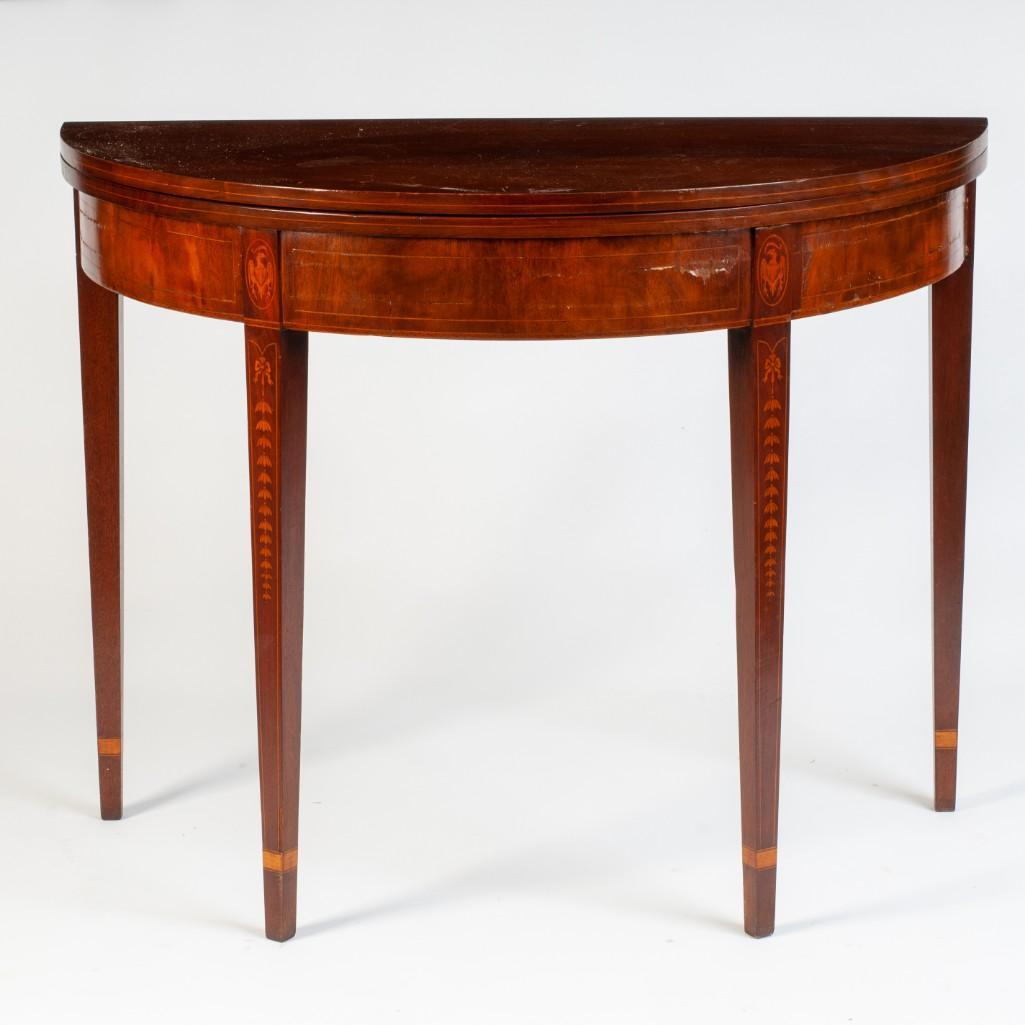 Federal Style Inlaid Mahogany Demilune Card Table.: In the Baltimore style, the demilune top above the frieze inlaid with a pair of eagle medallions, the tapered legs inlaid on the front with ribbon-tied pendant bellflowers. Height 31 inches, width 39 
