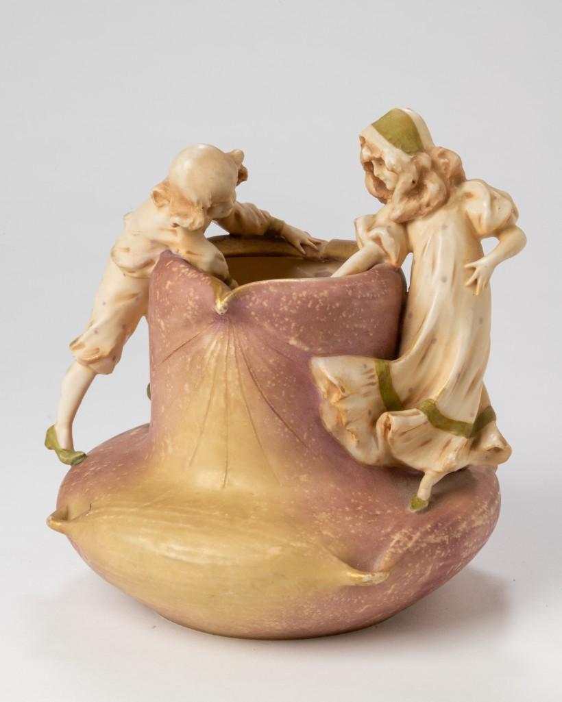 Amphora Pottery Figural Vase.: Height 7.25 inches, depicting a boy and a girl, marked Amphora 1323 with crown mark.