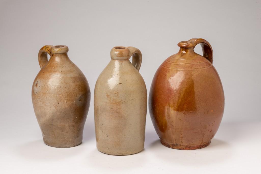 Three Early Stoneware Jugs.: A redware example, height 9 inches, and two others.