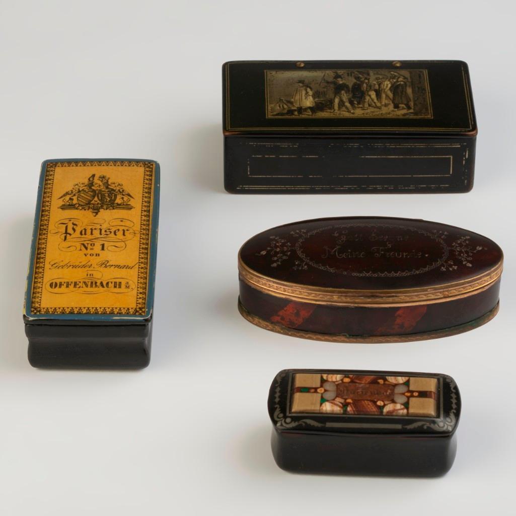 Four Snuff Boxes.: The first, German, papier mache, black with gold decoration of a group of men in uniform marching another man in the street circa 1820, length 4.25." The second, German, inlaid with stones from the sp