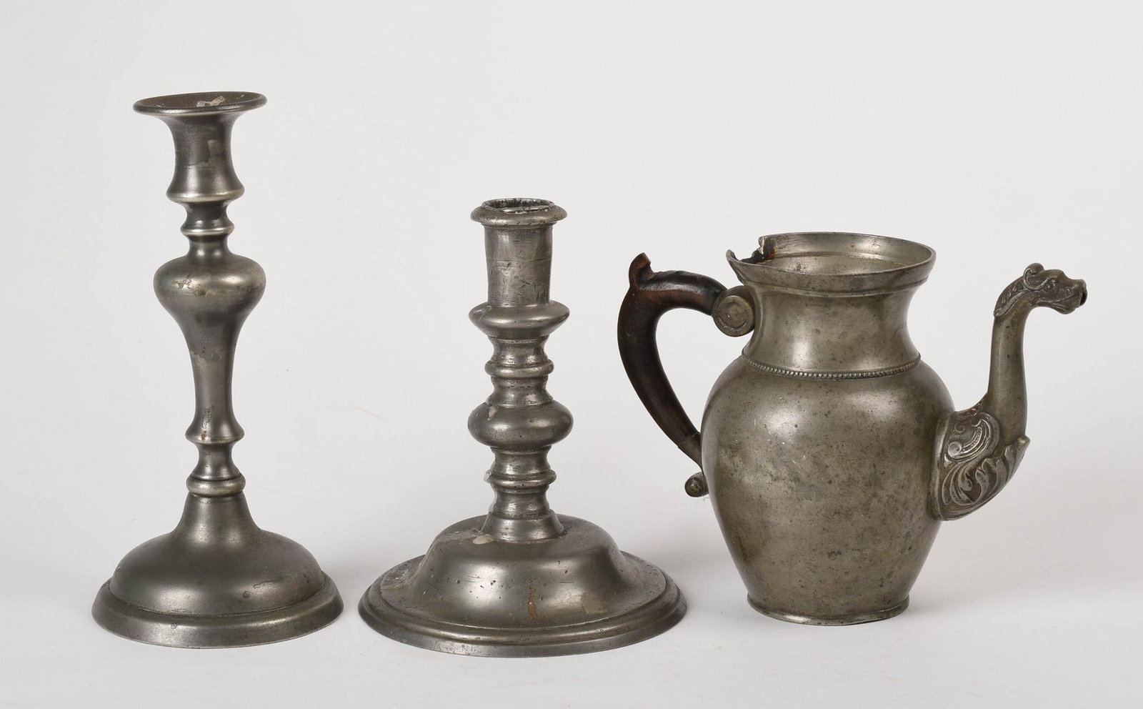 Three Pewter Items.: A Belgian coffeepot with dragon spout, height 6.25 inches, missing lid. Two candlesticks, heights 8.75 and 7 inches.