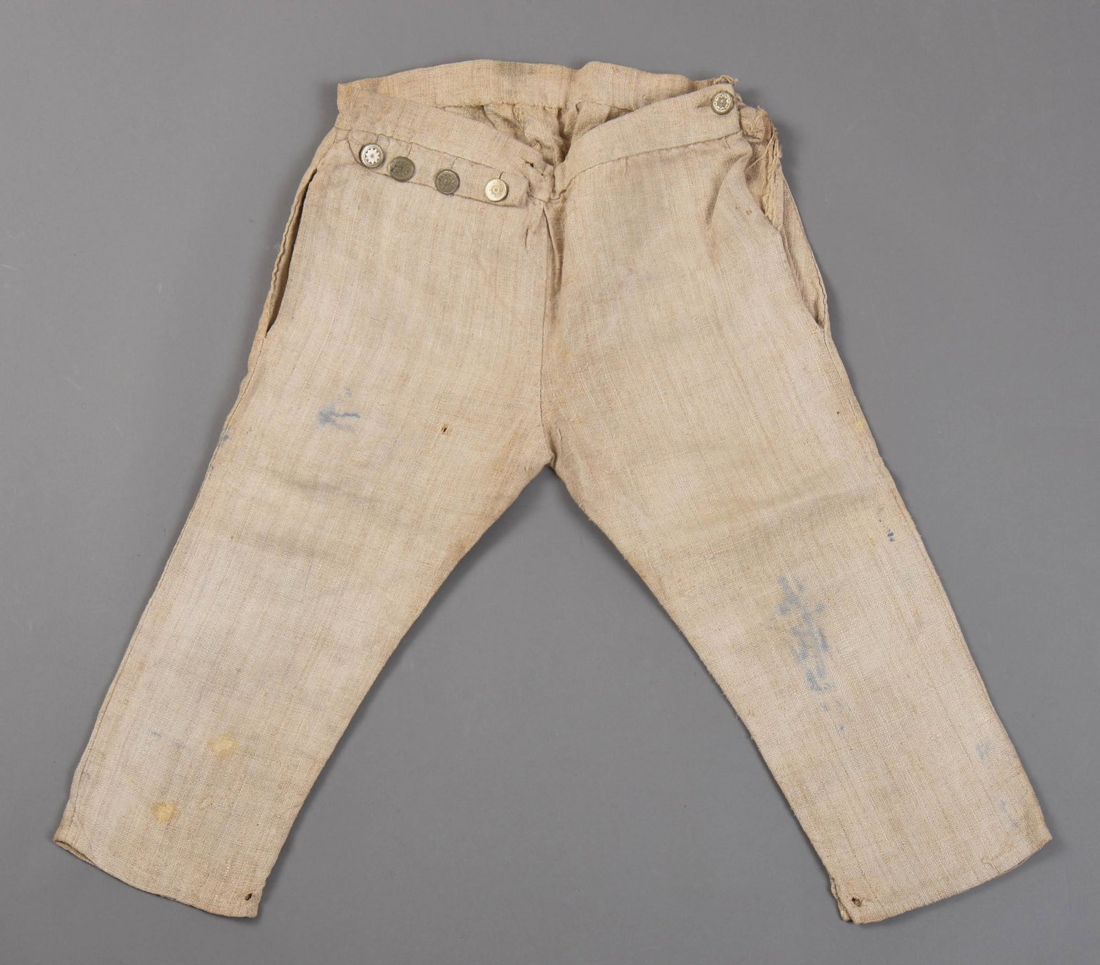 Sailor’s Working Breeches of Sailcloth, c. 1830: A pair of breeches that are sailor-made from old hempen sailcloth and also appear to have been altered into its current configuration from a front fly opening, to an opening on the left inseam, the wa