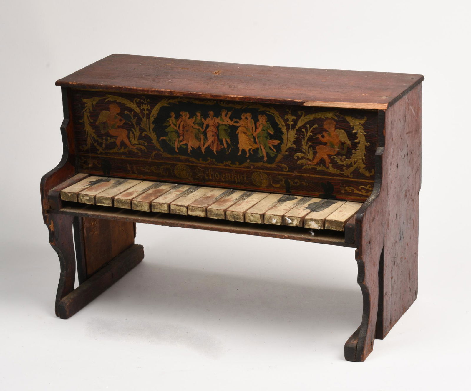 Schoenhut Toy Piano.: Decorated with cherubs and dancing ladies. Length 16 inches, height 12 inches. Break to top, losses to finish.